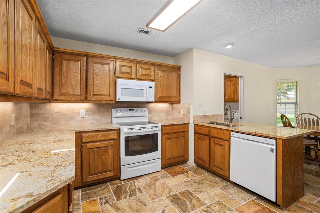 5522 Wedgefield Road Granbury, TX 76049 - Photo 8 of 22 a kitchen with stainless steel appliances granite countertop a stove a sink and a microwave