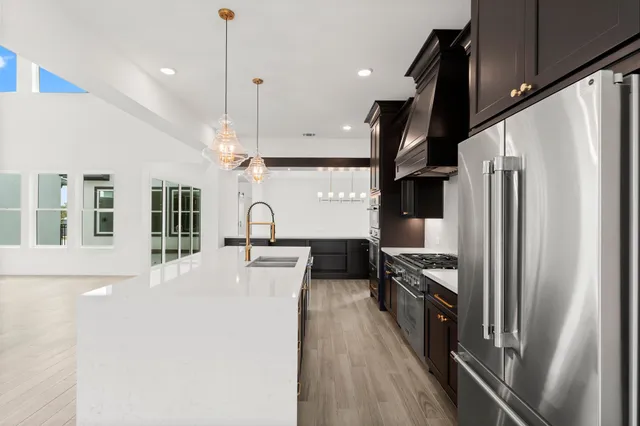 a large kitchen with stainless steel appliances granite countertop a stove and a wooden floors