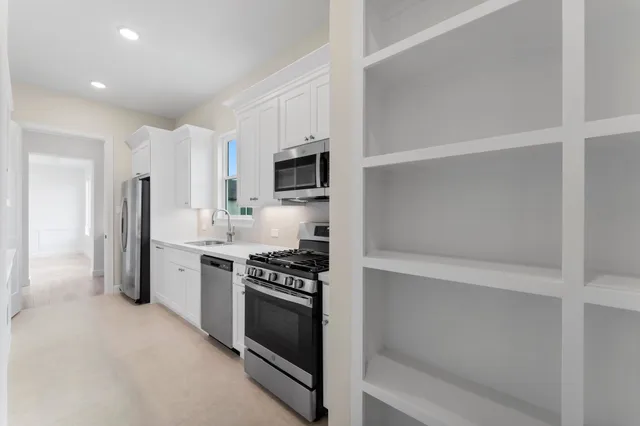 a view of a kitchen with a refrigerator a ceiling fan and wooden floor