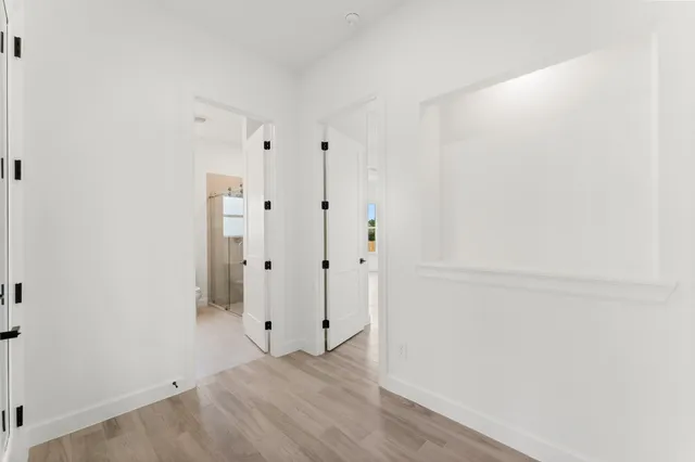 a view of an empty room with a window and wooden floor