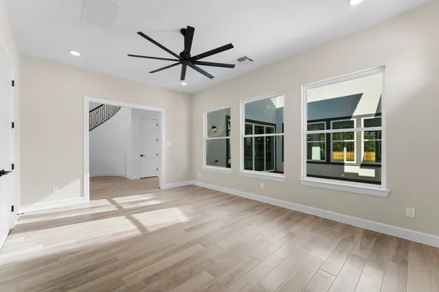 a view of an empty room with a window and wooden floor