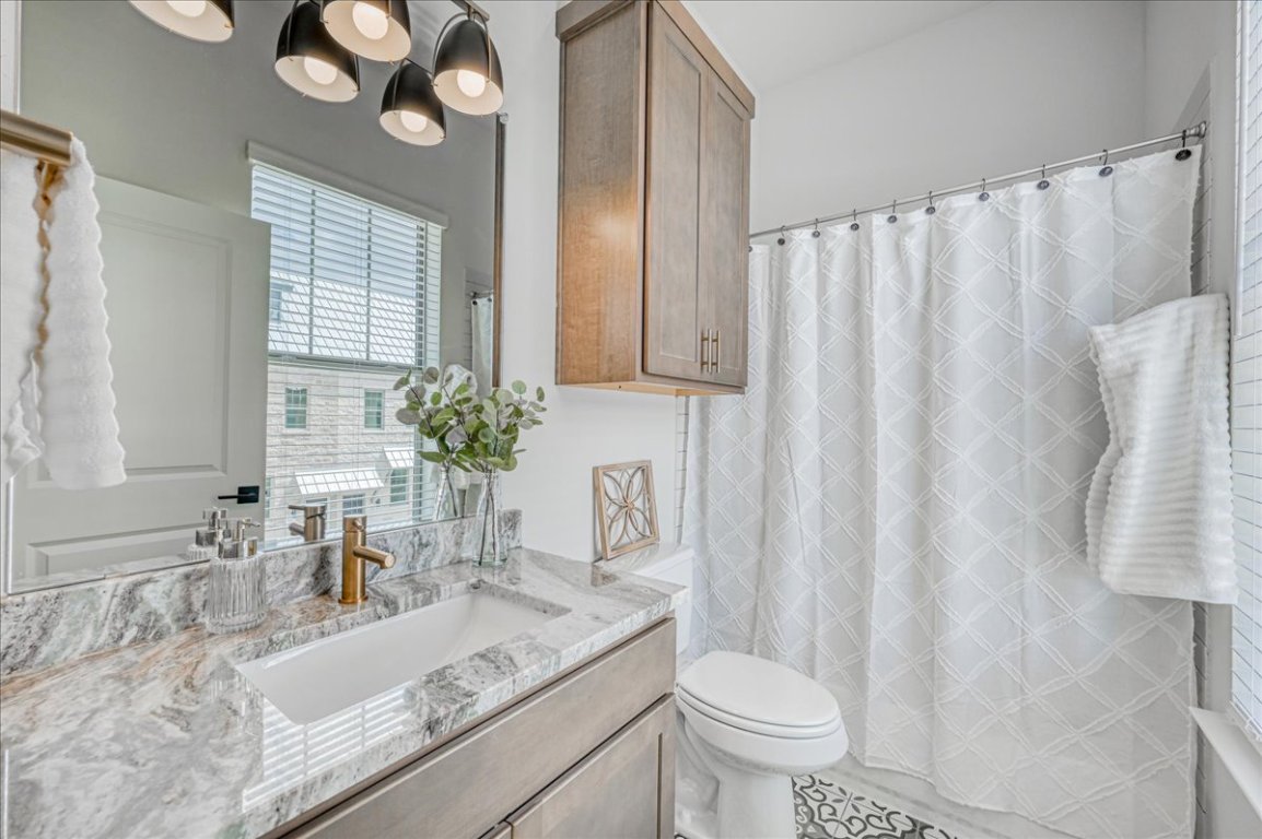 905 Pullman Street Leander, TX 78641 - Photo 18 of 31 a bathroom with a granite countertop sink a toilet and a mirror