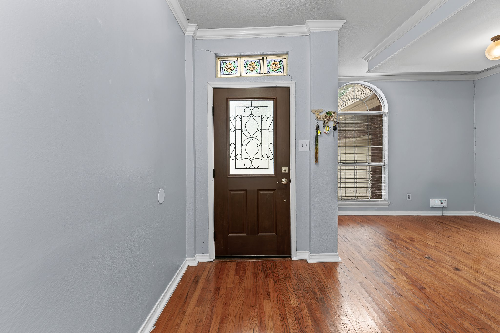 11737 Rydalwater Lane Austin, TX 78754 - Photo 4 of 40 Entryway featuring a dark wood-finish door with decorative glass and wrought iron detailing, complemented by a stained-glass transom window