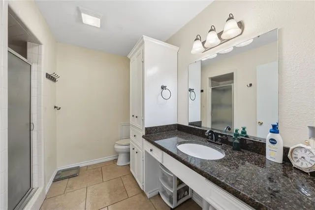 a bathroom with a granite countertop sink a toilet and a mirror