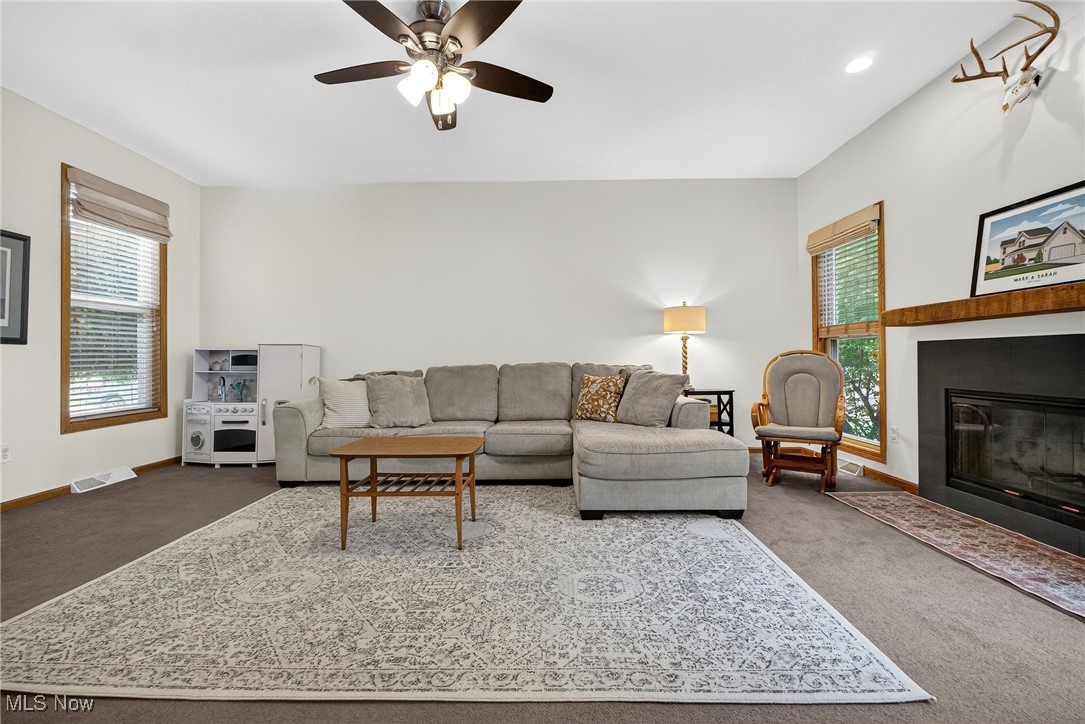 35748 Mills Road Avon, OH 44011 - Photo 9 of 44 Living area with dark colored carpet, a fireplace with flush hearth, and a ceiling fan