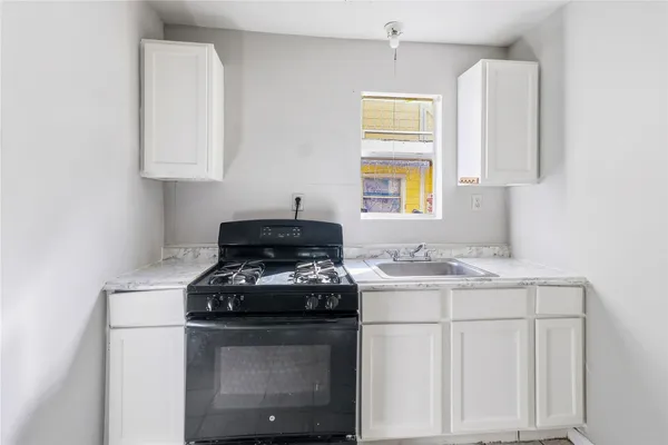 a kitchen with granite countertop a sink stove and cabinets