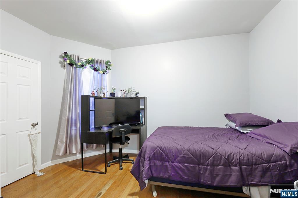 119 Ridgewood Avenue Newark, NJ 07108 - Photo 35 of 38 a bedroom with a bed table chair and a flat screen tv