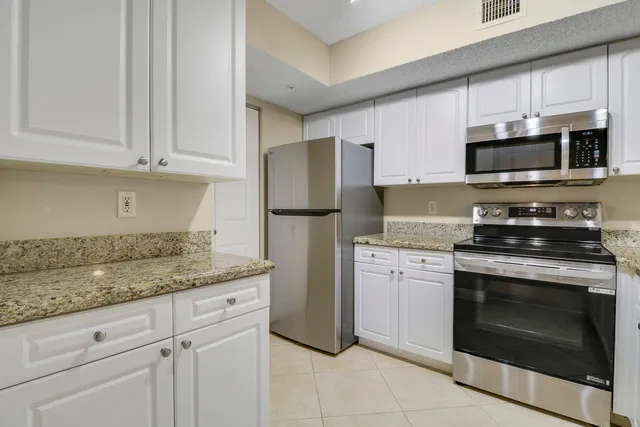 a kitchen with granite countertop white cabinets stainless steel appliances and a sink