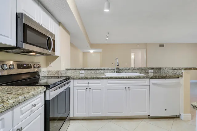a kitchen with granite countertop a sink and stainless steel appliances