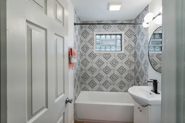 a bathroom with a sink and mirror with bathtub