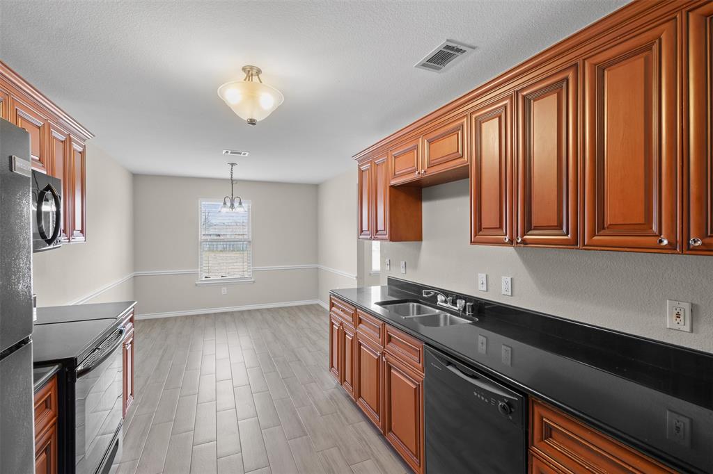 503 Caddell Street Aubrey, TX 76227 - Photo 16 of 39 a kitchen with stainless steel appliances granite countertop a refrigerator a sink dishwasher a stove and white countertops with wooden floor