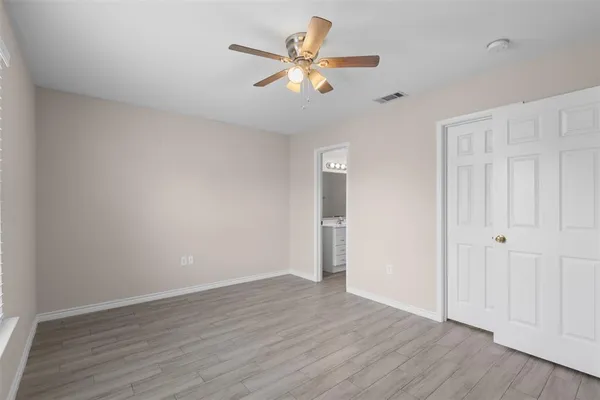 an empty room with wooden floor ceiling fan and window