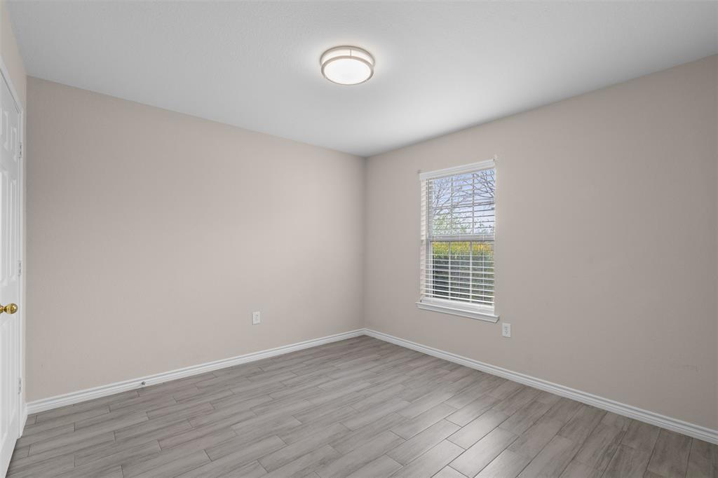 503 Caddell Street Aubrey, TX 76227 - Photo 32 of 39 a view of an empty room with wooden floor and a window