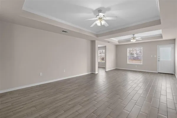 a view of an empty room with a window and wooden floor