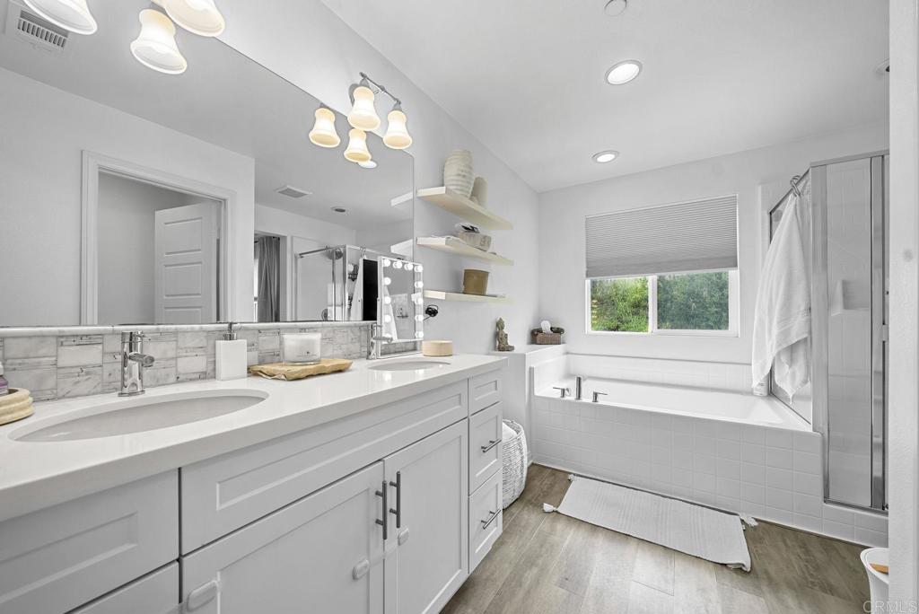 8614 Skylight Way El Cajon, CA 92021 - Photo 19 of 65 a spacious bathroom with a granite countertop sink mirror and a bathtub next to a window