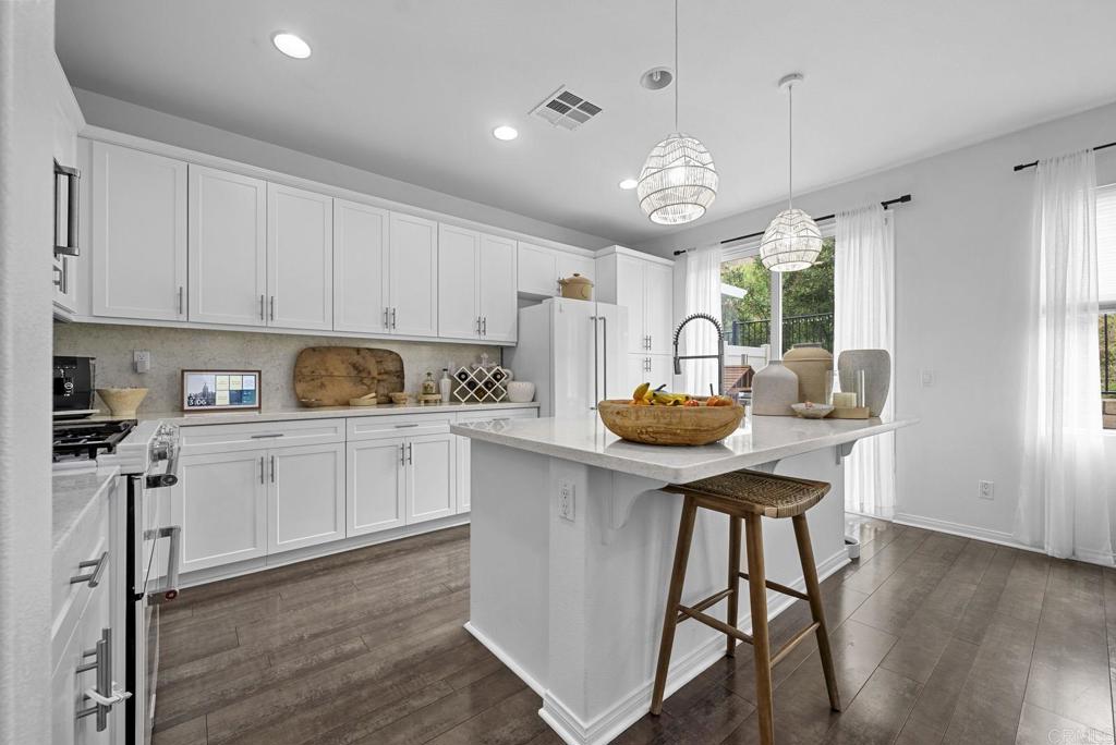 8614 Skylight Way El Cajon, CA 92021 - Photo 5 of 65 a kitchen with stainless steel appliances granite countertop a stove a refrigerator a sink dishwasher a dining table and chairs with wooden floor