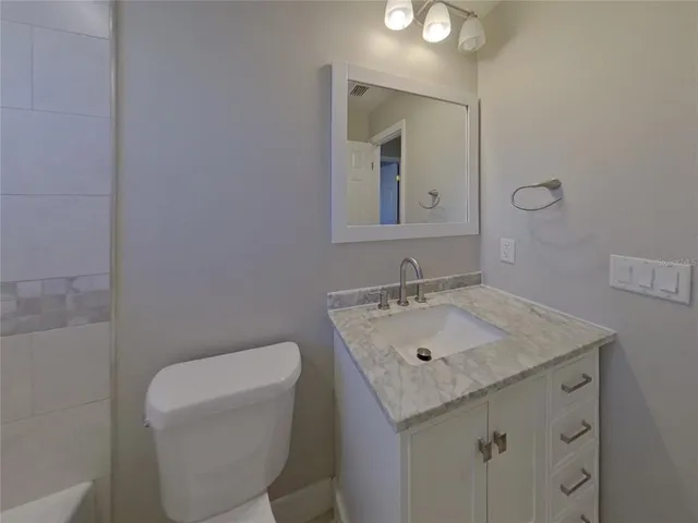 a bathroom with a granite countertop sink a toilet and mirror