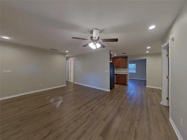 a view of an empty room with wooden floor and a ceiling fan