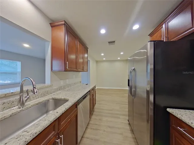 a kitchen with stainless steel appliances granite countertop a sink refrigerator and cabinets