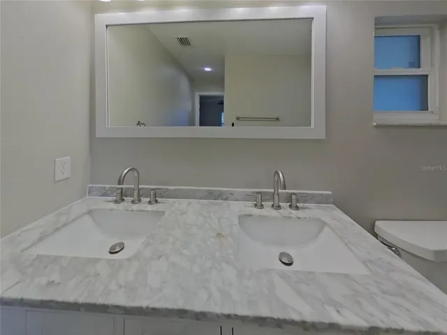 a bathroom with a granite countertop sink and a mirror