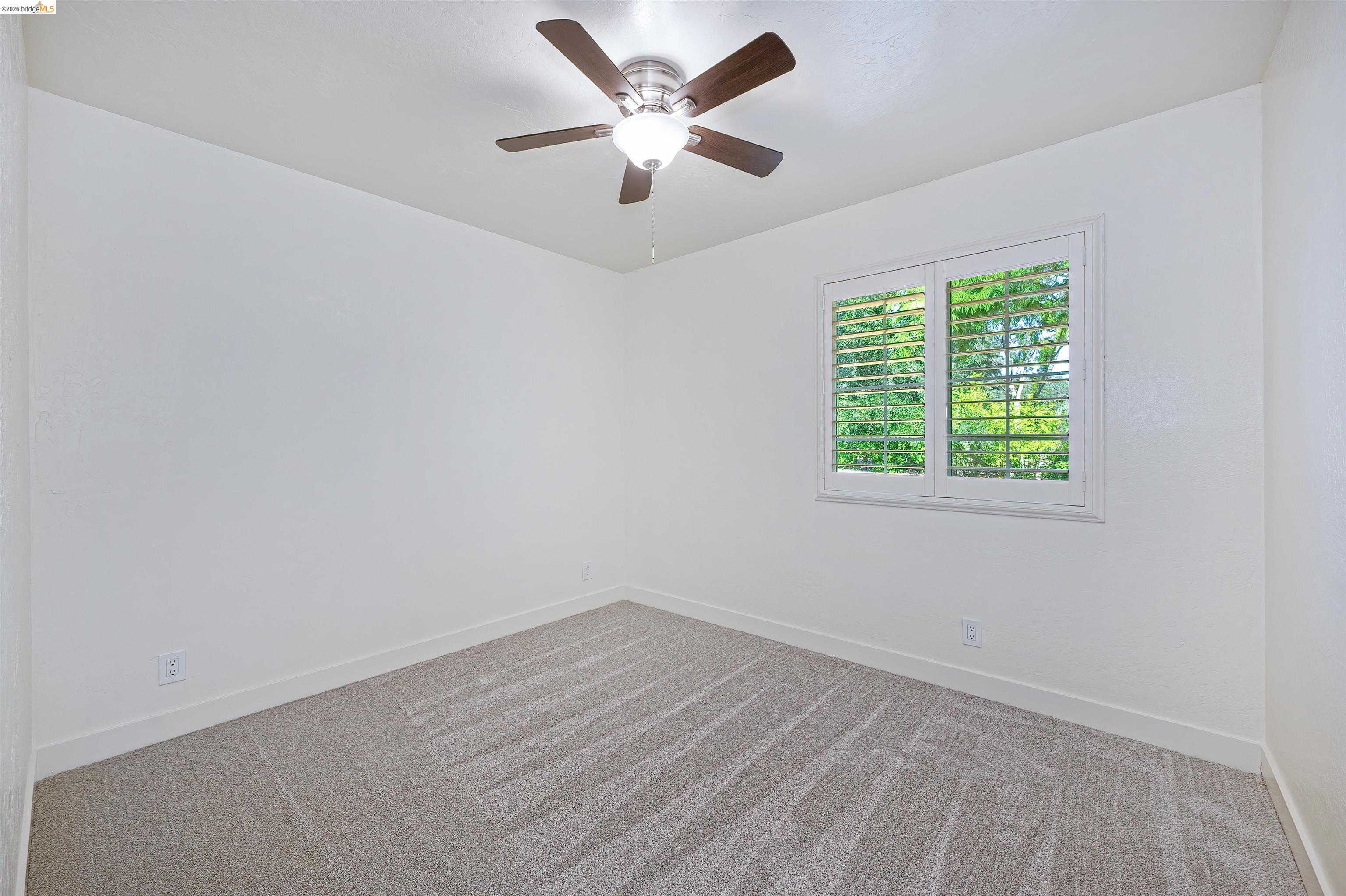 10474 Sheldon Road Elk Grove, CA 95624 - Photo 40 of 83 Bright interior space featuring a window with white plantation shutters, a ceiling fan with integrated lighting, and neutral carpet flooring