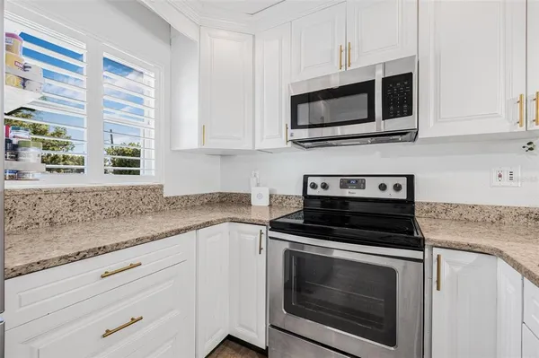 a kitchen with granite countertop white cabinets appliances and a sink