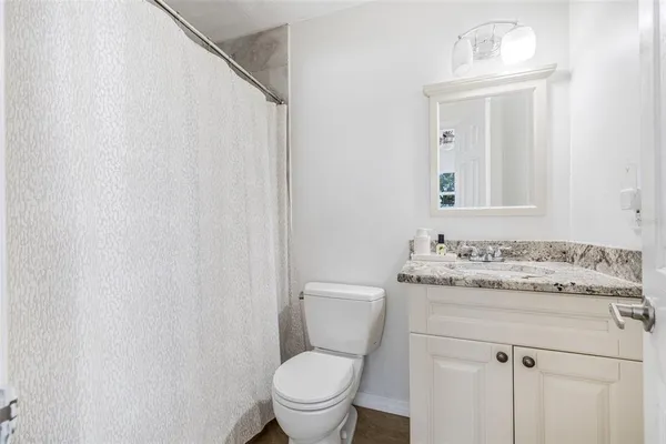 a bathroom with a granite countertop toilet sink and mirror