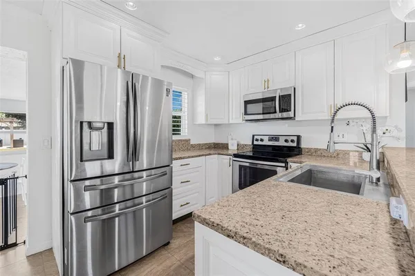 a kitchen with granite countertop a refrigerator stove and sink