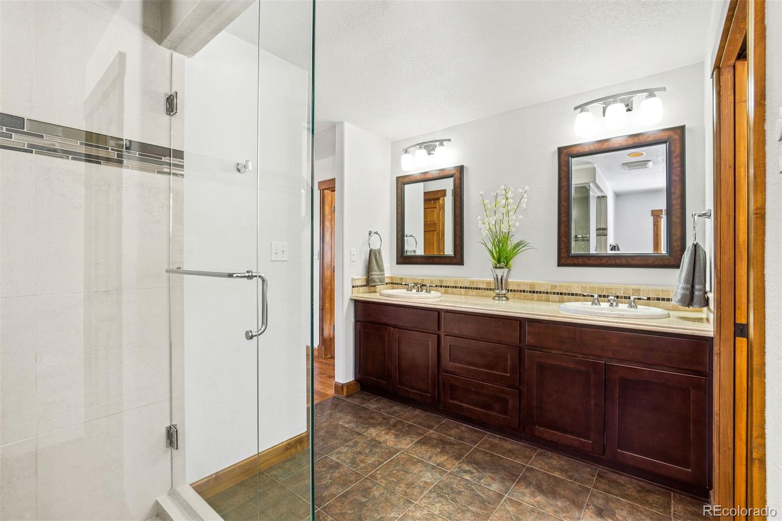 8331 South Warhawk Road Conifer, CO 80433 - Photo 21 of 40 a bathroom with a double vanity sink and a mirror