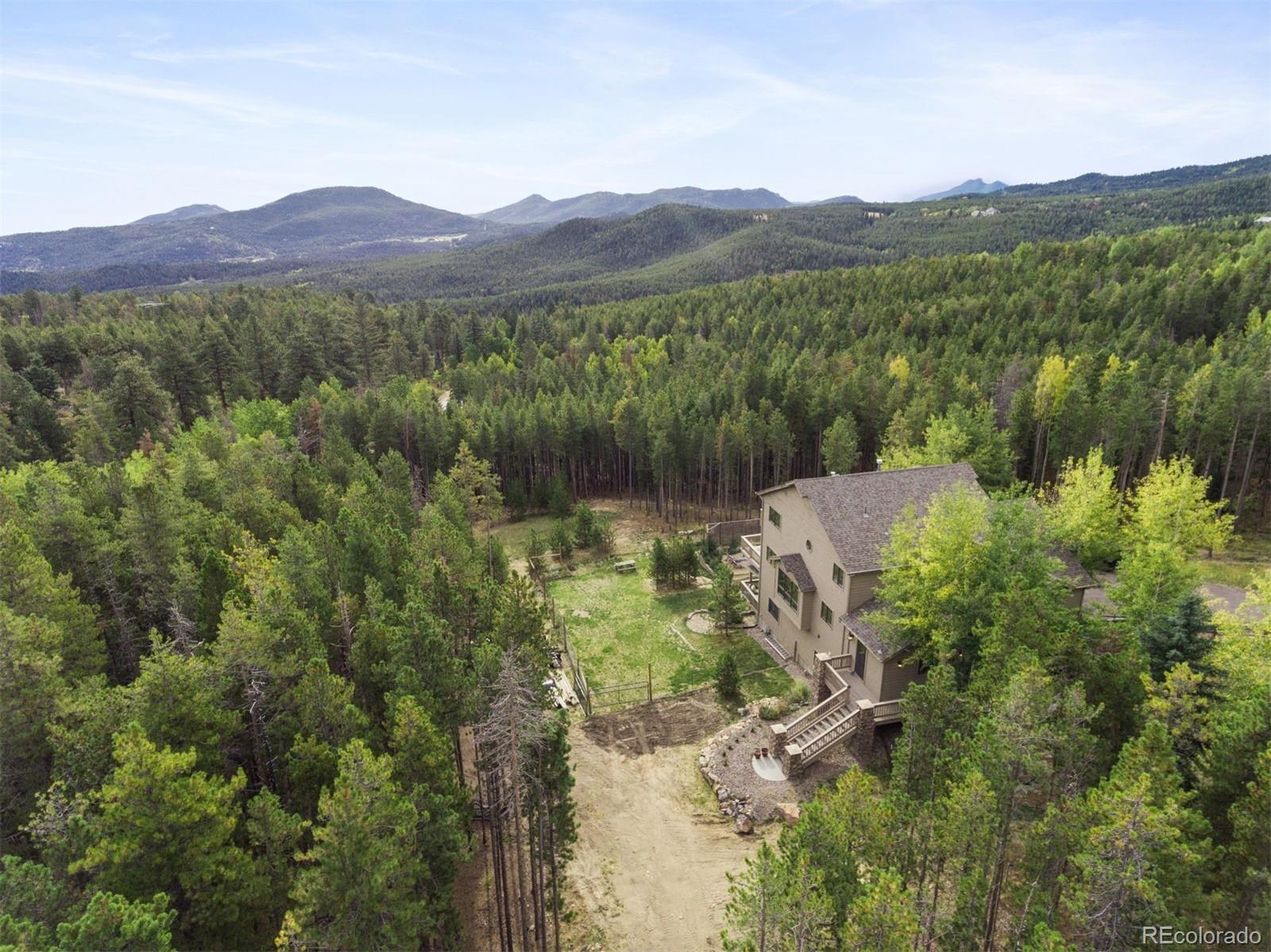 8331 South Warhawk Road Conifer, CO 80433 - Photo 36 of 40 a view of a lush green hillside and a building in the background