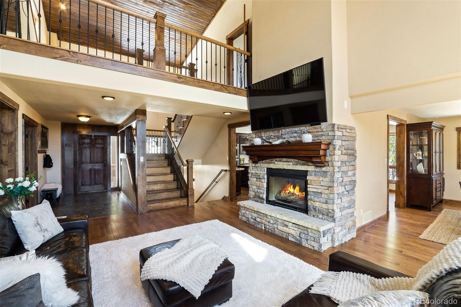 8331 South Warhawk Road Conifer, CO 80433 - Photo 6 of 40 a living room with furniture a flat screen tv and a fireplace