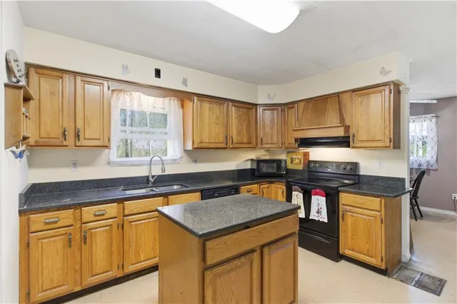 a kitchen with granite countertop a sink stove and cabinets