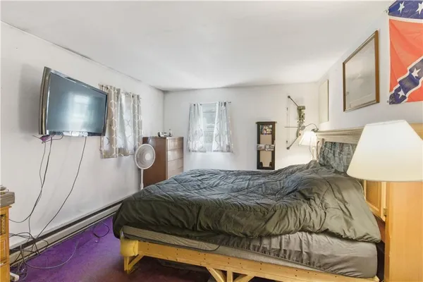 a bedroom with a bed and a flat tv screen on dresser