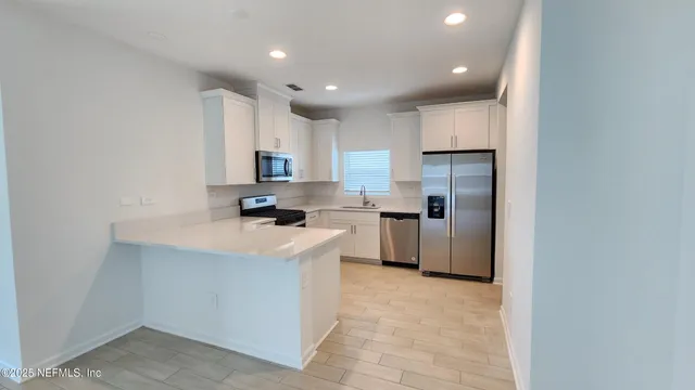 a kitchen with a sink a counter top space stainless steel appliances and cabinets