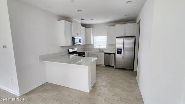 a kitchen with stainless steel appliances a refrigerator a sink a stove a microwave and island