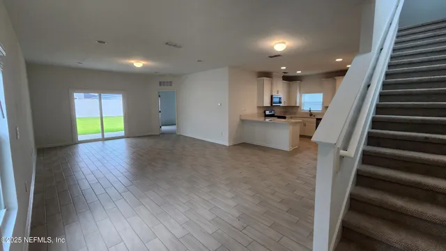 a view of an empty room with wooden floor and stairs