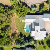 an aerial view of residential house with outdoor space and trees all around