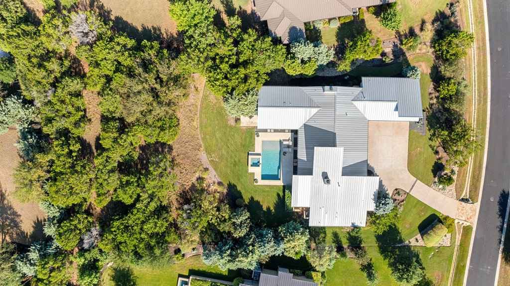 an aerial view of residential house with outdoor space and trees all around