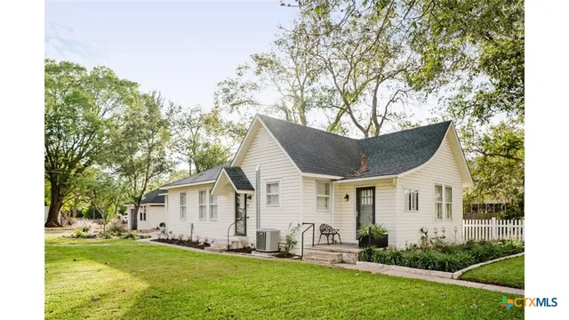 a front view of a house with a yard and trees