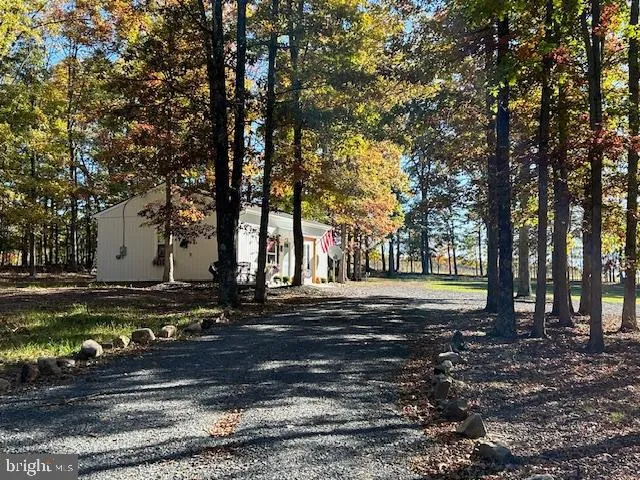 a view of house with a yard and large trees