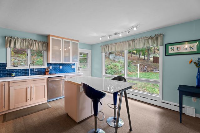 a kitchen with stainless steel appliances a refrigerator a stove a sink dishwasher and white cabinets with wooden floor