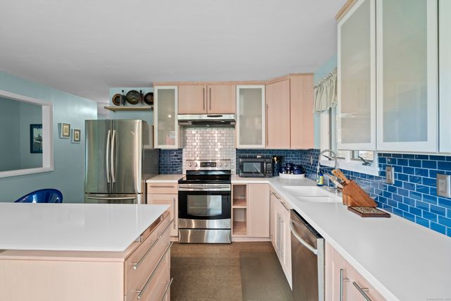 a kitchen with stainless steel appliances kitchen island a table chairs and a refrigerator