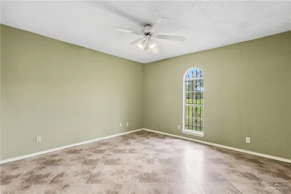 an empty room with windows and ceiling fan