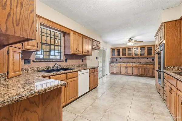 a large kitchen with stainless steel appliances granite countertop a stove top oven a sink a counter space and cabinets