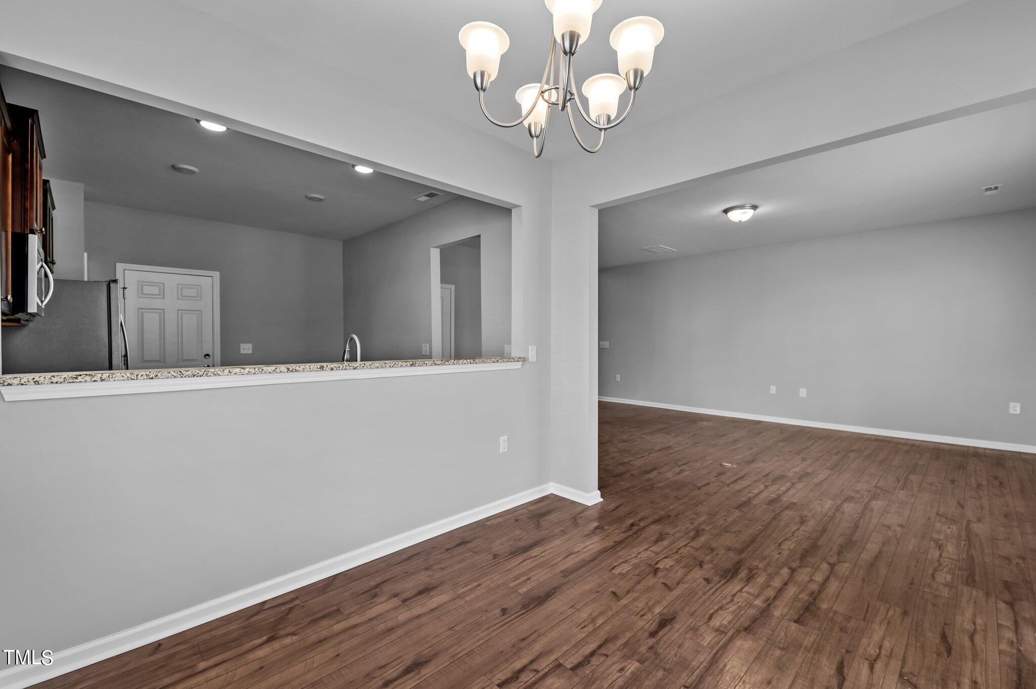 1033 Mirbeck Lane Durham, NC 27713 - Photo 17 of 37 an empty room with wooden floor and chandelier