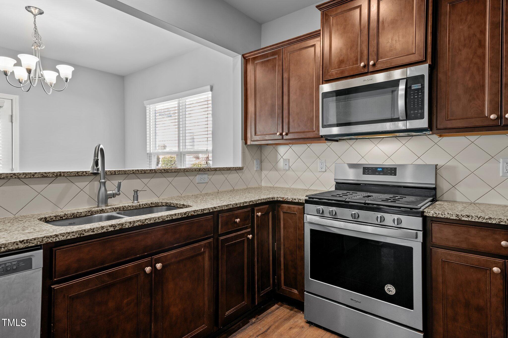 1033 Mirbeck Lane Durham, NC 27713 - Photo 9 of 37 a kitchen with granite countertop a stove top oven microwave and cabinets