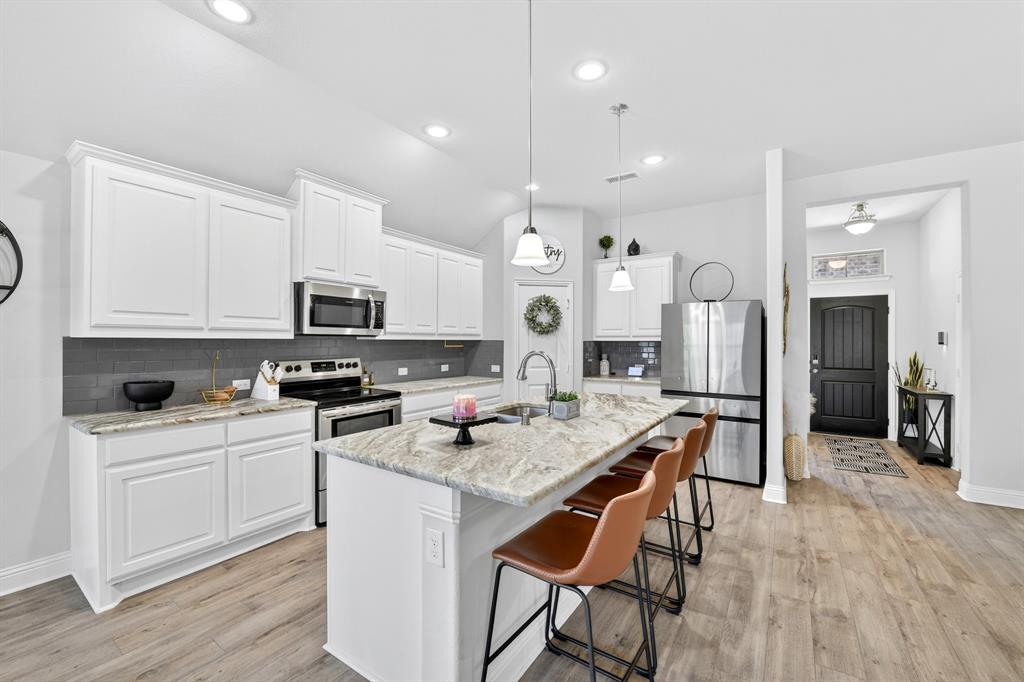 136 Gleeson Drive Red Oak, TX 75154 - Photo 11 of 40 a kitchen with stainless steel appliances granite countertop a stove top oven a refrigerator a sink and white cabinets with wooden floor