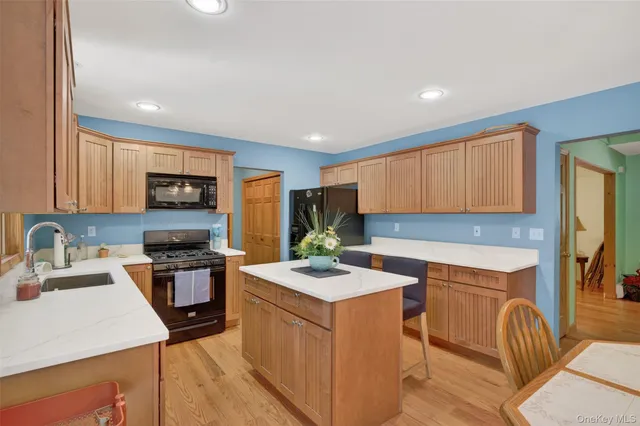 a kitchen with stainless steel appliances granite countertop a stove top oven a sink dishwasher and a refrigerator with wooden floor