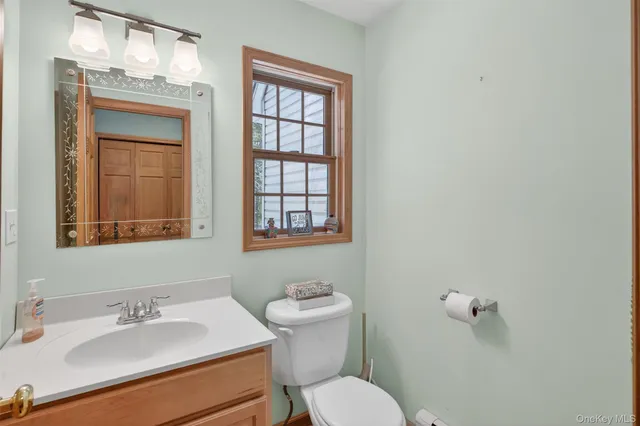 a bathroom with a sink mirror toilet and next to a window