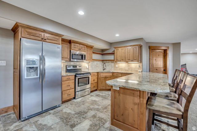 896 West 675 South Mapleton, UT 84664 - Photo 47 of 77 Kitchen with open shelves, stainless steel appliances, a peninsula, a breakfast bar, and light stone countertops